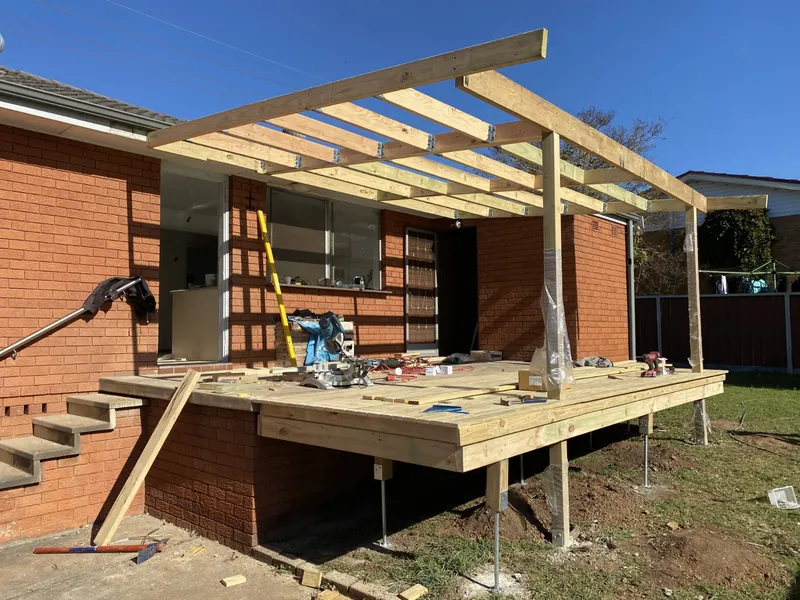 Chipping Norton: new timber deck and pergola framing at the back of a brick home