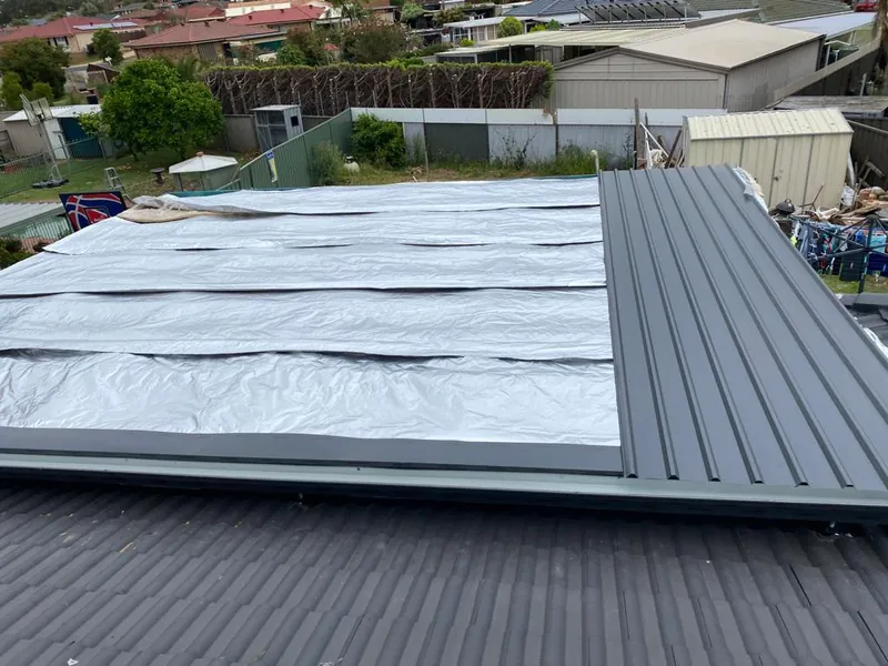 Metal roof sheets being laid over sarking on the new pergola roof